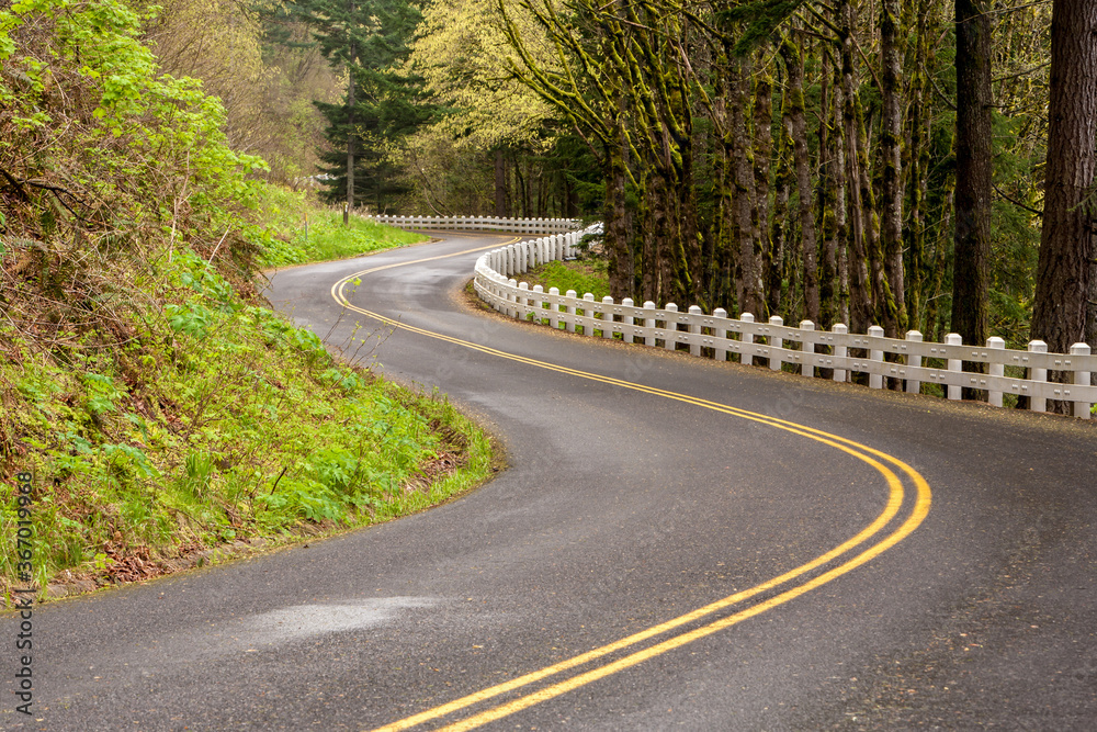 A winding section of the old Columbia River Highway near Multnomah Falls, Oregon.  Guard rail is the old wooden type.