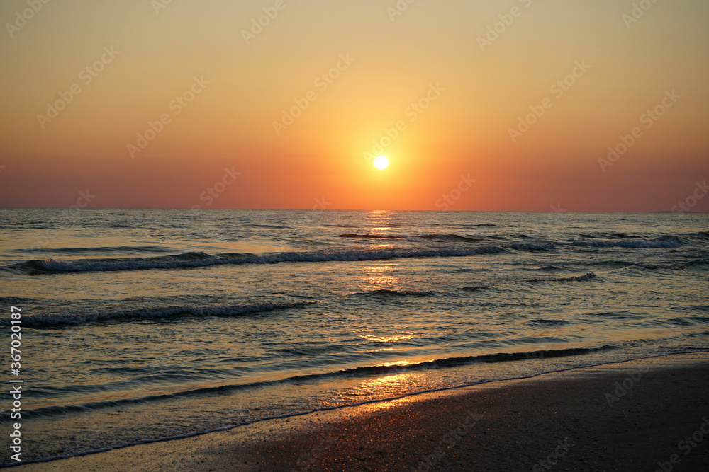 red sunset on the beach with beautiful sea, waves and orange sky.