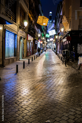 Street in the city of Madrid with Christmas decorations whose brightness is reflected in the ground or pavement