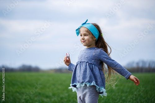 little girl child runs and jumps, green grass in the field, sunny spring weather, smile and joy of the child, blue sky with clouds © Дмитрий Ткачук