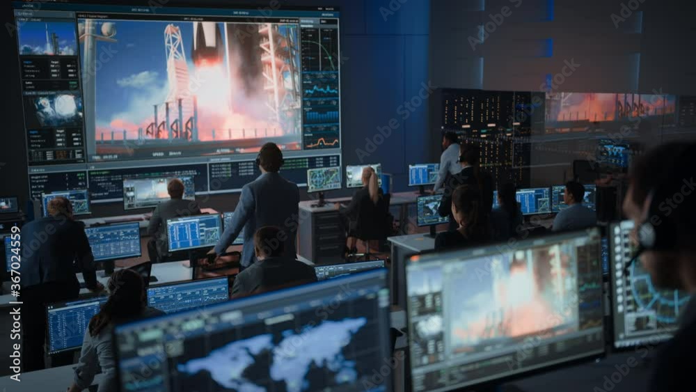 Group of People in Mission Control Center Witness Successful Space Rocket Launch. Flight Control Employees Sit in Front Computer Displays and Monitor the Crewed Mission. Team Stand Up and Clap Hands.