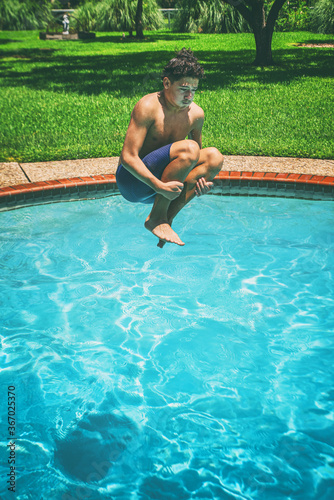 Teenager jumping into swimming pool on a sunny day