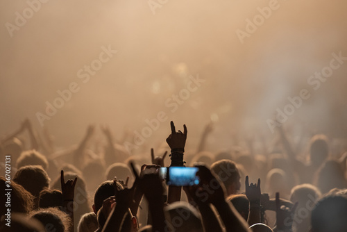 Hand raised showing a heavy metal rock sign at concert
