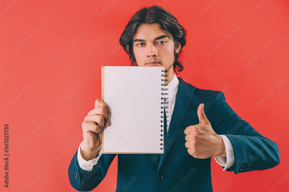 Businessman with a mock up notepad in his hands on a red background. Businessman with a mock up notepad in his hands on a red background.