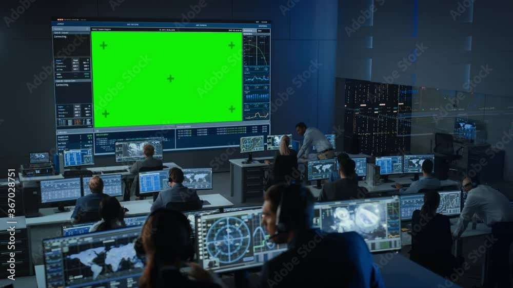 Big Green Screen Horizontal Mock Up in a Mission Control Center Room with Flight Director and Other Controllers Working on Computers. Team of Engineers Work in Monitoring Room Full of Displays.