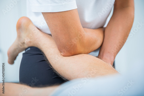 Physical therapist for adult men performs a therapeutic stretching