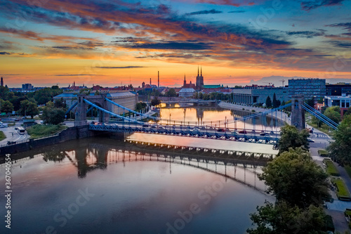 Drone view on the Grunwaldzki Bridge above Oder river in Wrocław at beautiful sunset. Rushing traffic, illuminated historic buildings and bridges. Beautiful sky, light reflections on the blurry water
