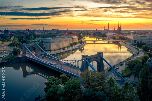 Aerial view from drone on the Grunwaldzki Bridge at sunset. Rushing traffic, illuminated historic buildings and bridges. Beautiful sky, lot of warm light and reflections on the blurry water
