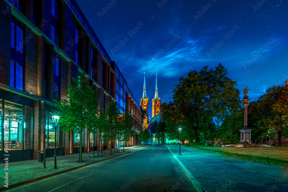 Obraz premium Noctilucent clouds in the upper atmosphere of Earth seen above Wroclaw in Poland. Beautiful night shining clouds in the mesosphere and stars over city famous historical ancient landmarks at dusk
