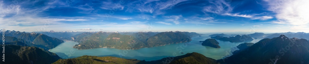 Aerial Panoramic View of Howe Sound and Beautiful Canadian Mountain Landscape during sunny and cloudy day. Taken near Squamish and Vancouver, British Columbia, Canada. Nature Background Panorama