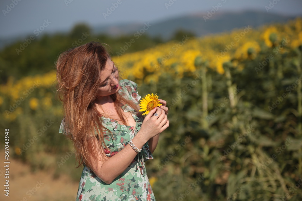 Beautiful young woman in a field of sunflowers in a green dress Beautiful young woman in a field of sunflowers in a green dress