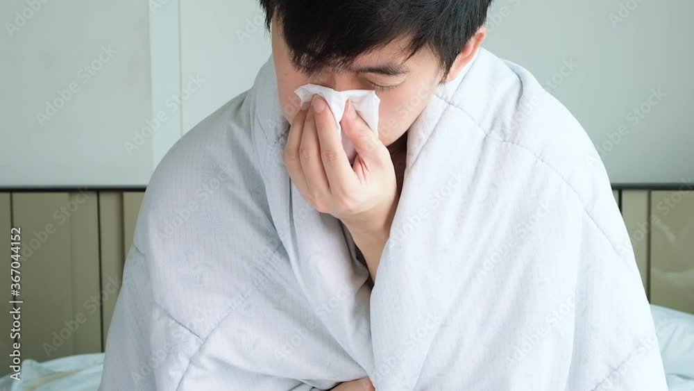 Sick man is flu, using a paper napkin and he have a runny nose. And he was covered in warm cloth.Health concept Sick man is flu, using a paper napkin and he have a runny nose. And he was covered in warm cloth.Health concept