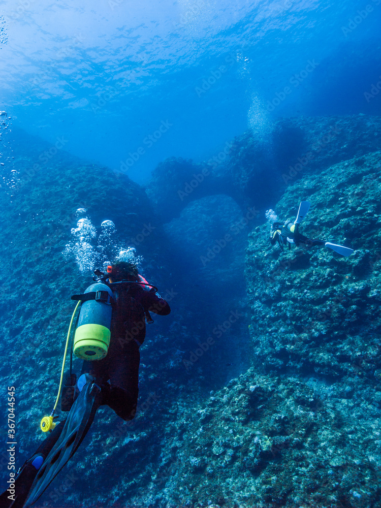 Scuba diver and coral reef. Divers are going into the underwater valley. Island, Okinawa, Japan Scuba diver and coral reef. Divers are going into the underwater valley. Island, Okinawa, Japan