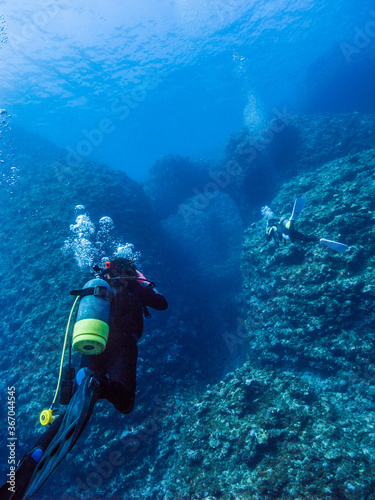 Scuba diver and coral reef. Divers are going into the underwater valley. Island, Okinawa, Japan 
