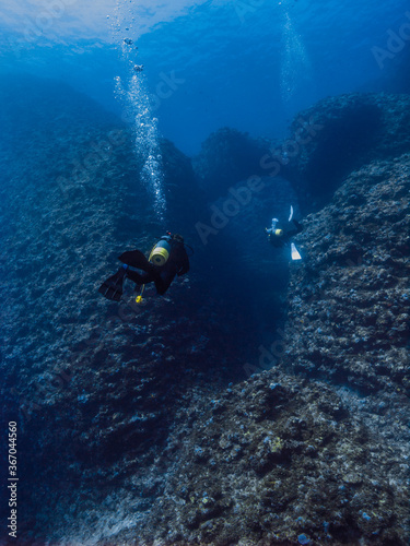 Scuba diver and coral reef. Divers are going into the underwater valley. Island, Okinawa, Japan 