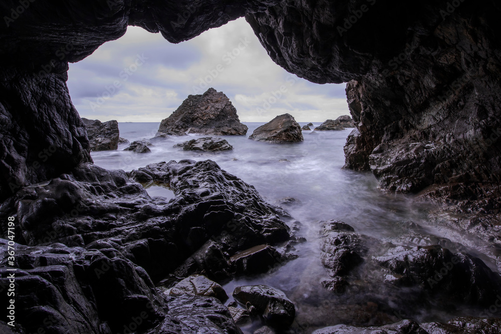 Curious and beautiful of the aeches in the rock cave in the early morning,long exposure sea wave.	