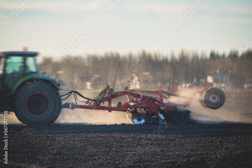 Fotografia, Obraz Tractor with a disc harrow system harrows the cultivated farm field, process of