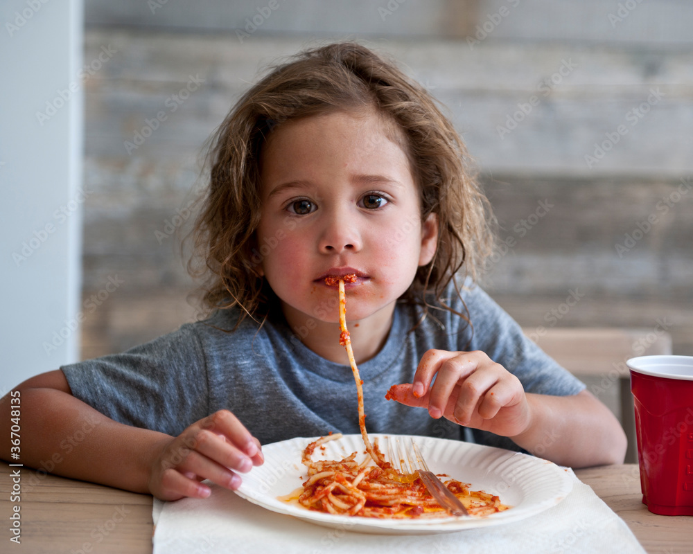 Young girl plays with spaghetti as she eats. Young girl plays with spaghetti as she eats.