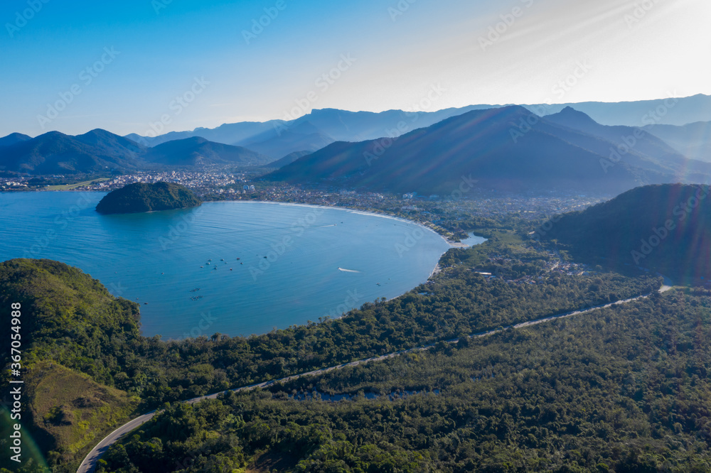 Paisagem captada com drone incluindo linda praia paraalela com a rodovia e montanhas.