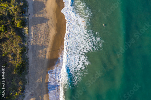 Foto aérea de praia cobrindo o oceano e sua vegetação da orla. Paisagem vista por cima.