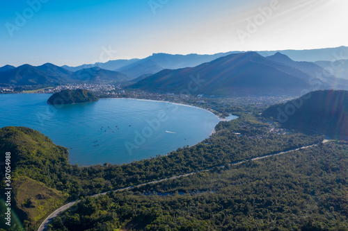 Paisagem captada com drone incluindo linda praia paraalela com a rodovia e montanhas.