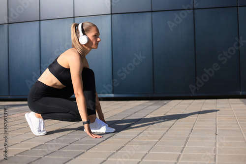 Athletic woman in sports clothing standing on the start line while running outdoors. © ty