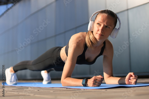 Sport girl doing plank exercise outdoor in warm summer day.