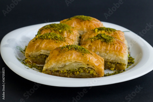 Traditional Turkish Pastry Dessert,Pistachio Baklava in plate at black surface with copy space