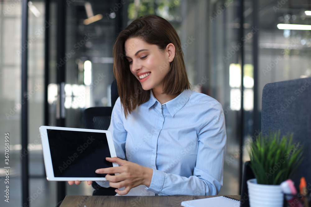 Young happy business woman showing blank tablet computer screen in office. Young happy business woman showing blank tablet computer screen in office.