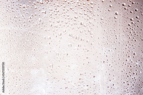 Water drops on a blurred background in close-up. Raindrops on a sunset background. Water on glass. Drops hang