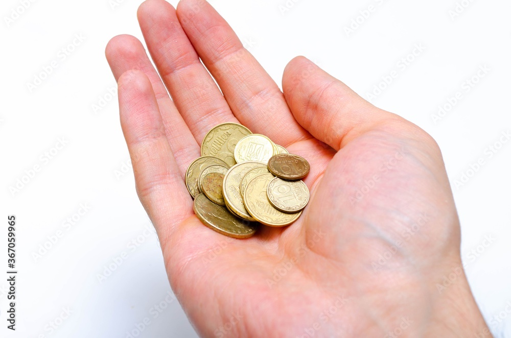Ukrainian coins on a white background in close-up. Coins in a heap close-up, in the form of a falling pyramid, in a man's hand