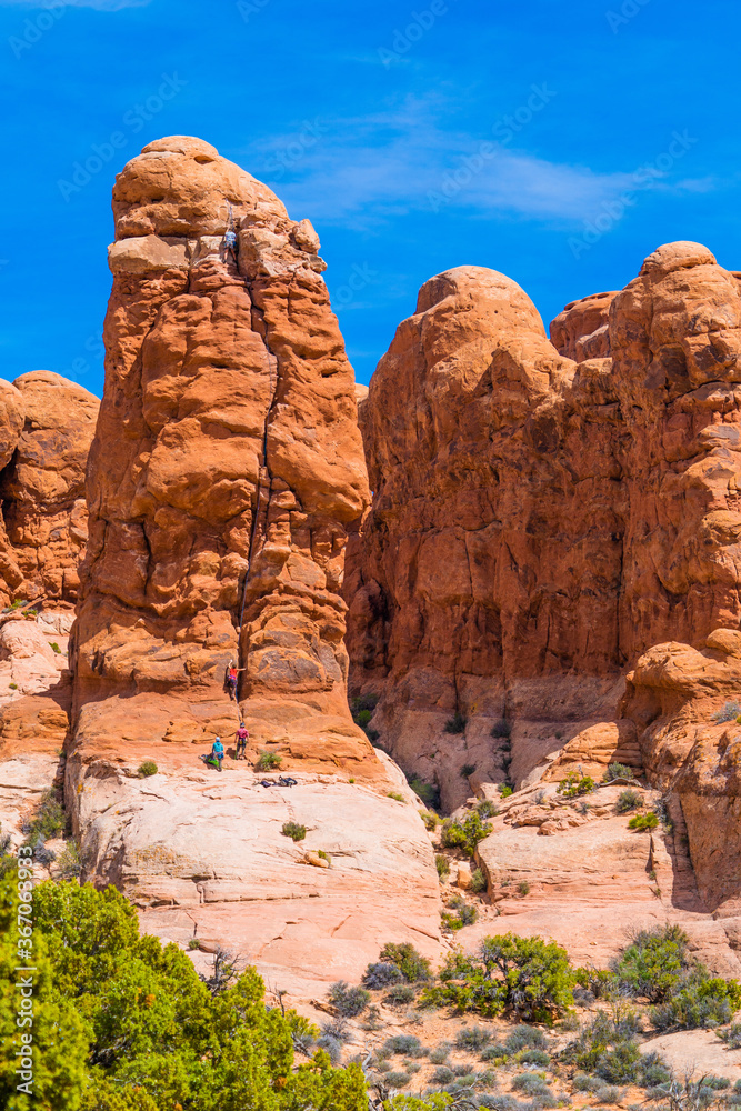 Fototapeta premium Rock climbers scaling steep pillars in Arches National Park, Utah