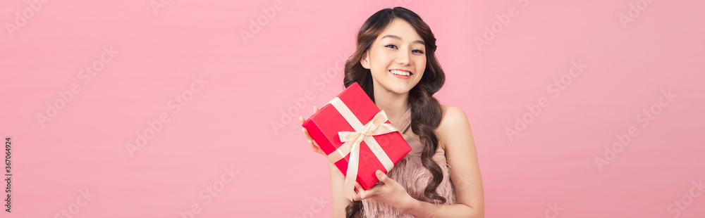 Young woman holding gift box with biege bow being excited and surprised holiday present Young woman holding gift box with biege bow being excited and surprised holiday present