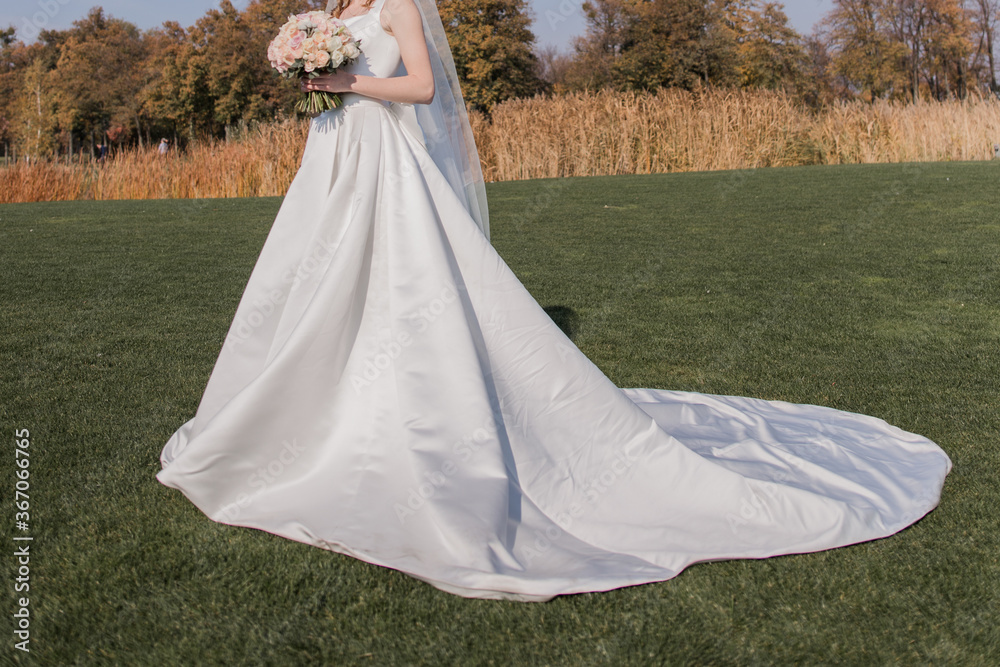 bride in a wedding dress in a field with a bouquet