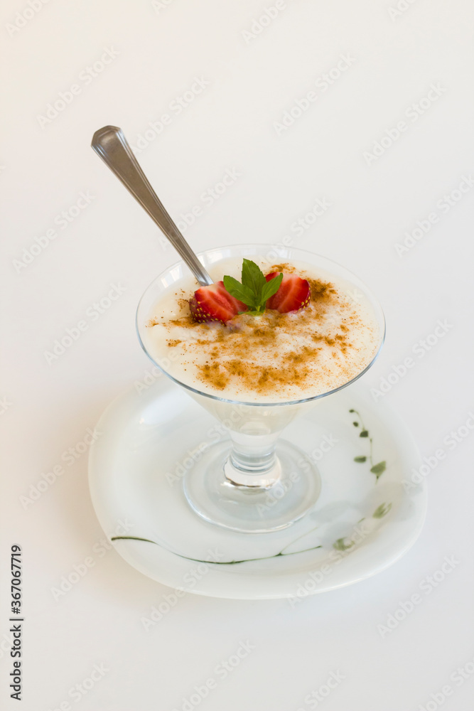 Traditional Turkish Rice Puding in stylish glass bowl wwith spoon on white background. Traditional Turkish Rice Puding in stylish glass bowl wwith spoon on white background.