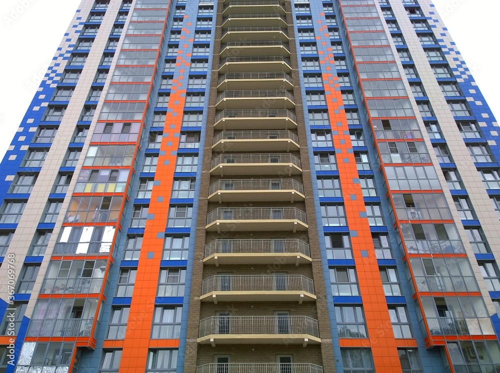 Fototapeta premium Multicolored facade of new multi-story residential building. Sale and rental apartments and comfortable housing. Cityscape. Windows and balconies. City living. Real estate investing. Mortgage concept