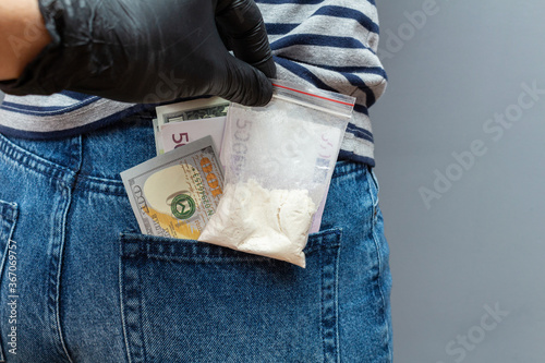 Drugs packet and money banknotes found in pocket during a police search with hand in black glove