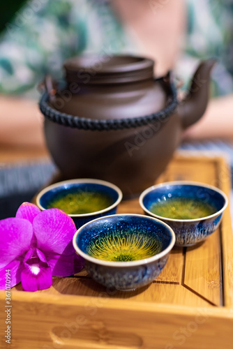 tea ceremony in the east, clay teapot and green tea cup decorated with orchid flower, Chinese tradition of tea drinking
