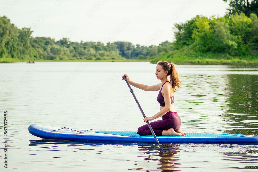 woman on sup sup board in nature at evening