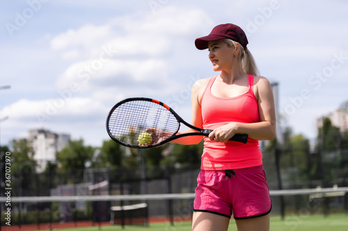 Woman playing tennis holding a racket and smiling