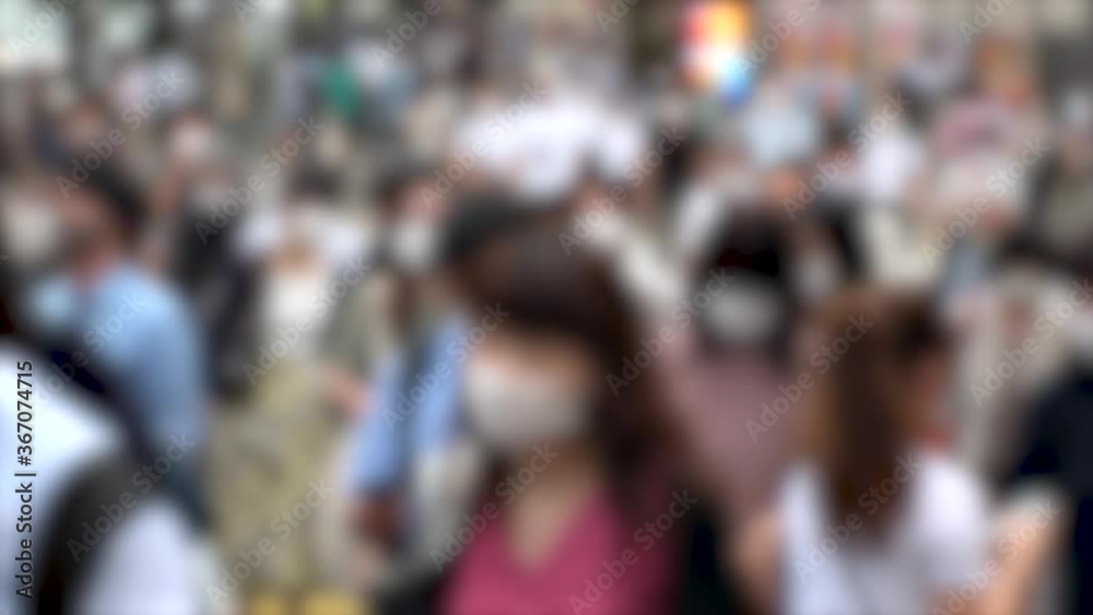 TOKYO, JAPAN - JUL 2020 : Crowd of people at the street near Shinjuku station in rush hour. Commuters wearing surgical mask to protect from Coronavirus (COVID-19) in hot summer. Blurred slow motion. TOKYO, JAPAN - JUL 2020 : Crowd of people at the street near Shinjuku station in rush hour. Commuters wearing surgical mask to protect from Coronavirus (COVID-19) in hot summer. Blurred slow motion.