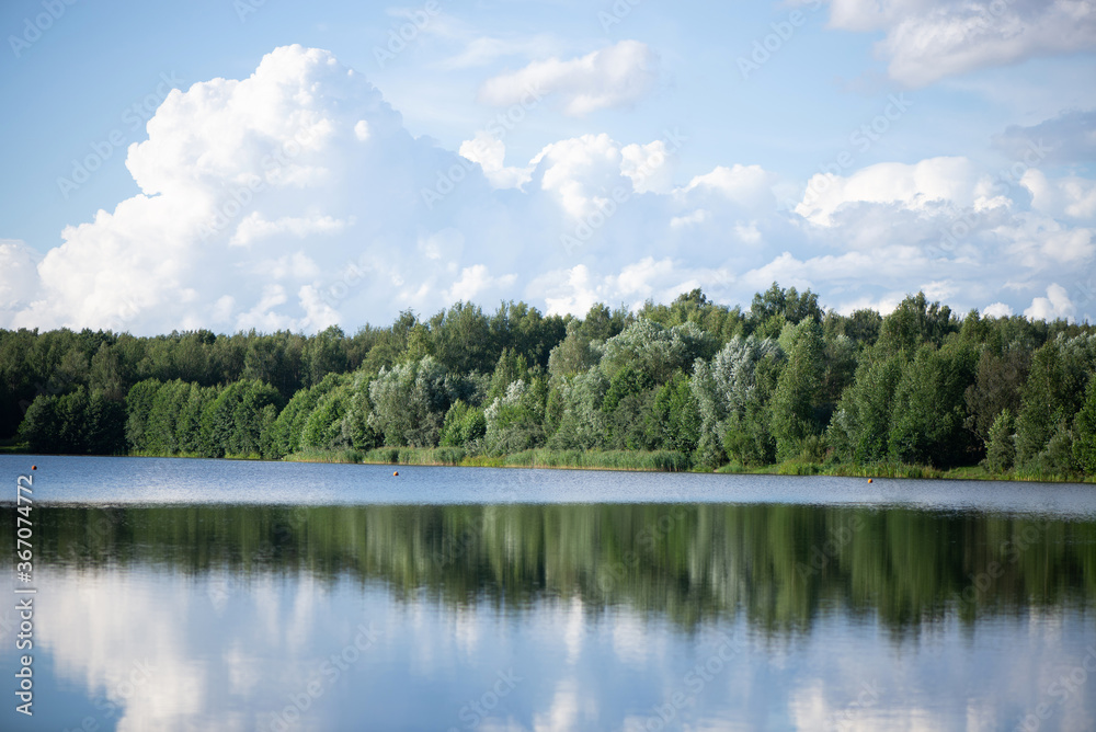Summer forest lake with clouds reflected in water landscape