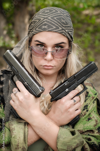 Beautiful and attractive female army soldier posing with two guns. Woman with weapon. Firearm shooting range gun shooting training. Fashion model style