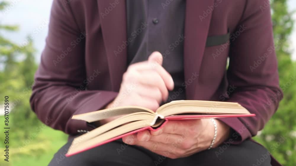 Male businessman, manager or student reads a book outdoors in the park Male businessman, manager or student reads a book outdoors in the park