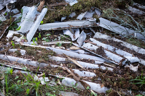 Broken asbestos cement sheets in nature, toxic waste photo