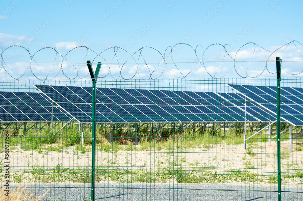 Alternative energy source, solar panels, green energy. Behind a metal fence with barbed wire. Alternative energy source, solar panels, green energy. Behind a metal fence with barbed wire.