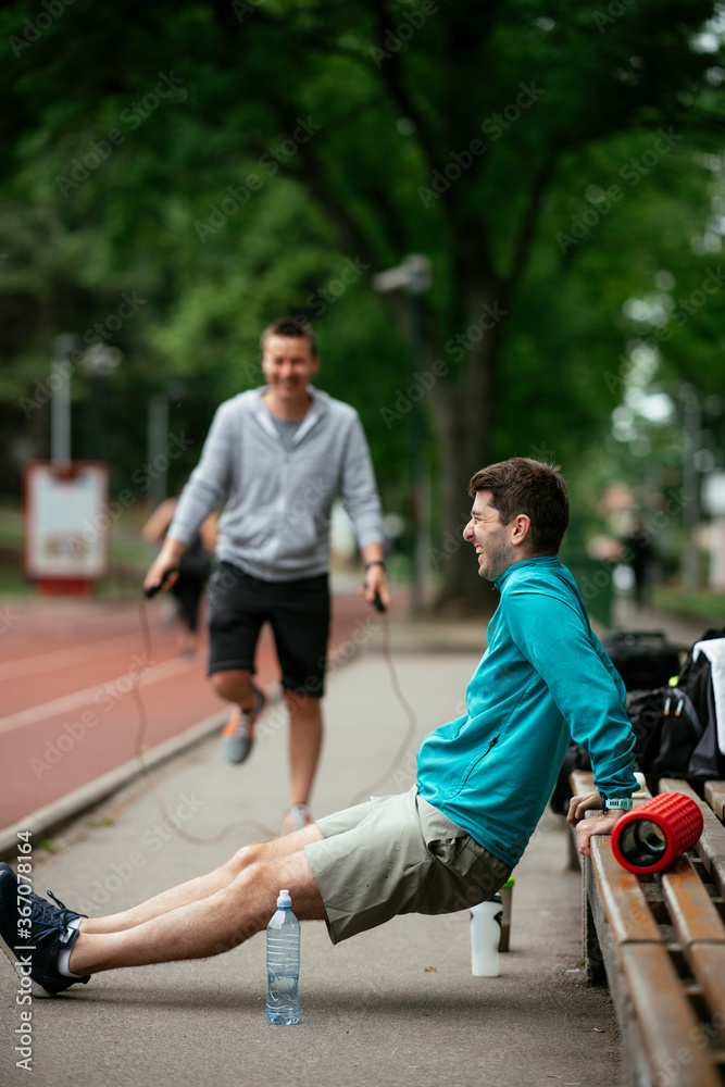 Young men exercising on a race track. Two young friends training outdoors.
Young men exercising on a race track. Two young friends training outdoors.