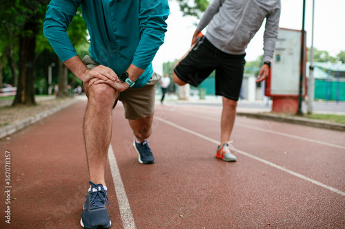 Young men exercising on a race track. Two young friends training outdoors. 