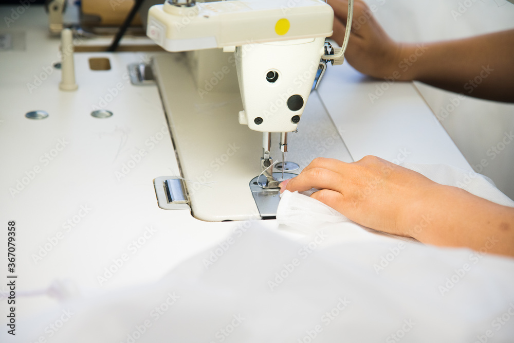 Woman hands with fabric at sewing machine