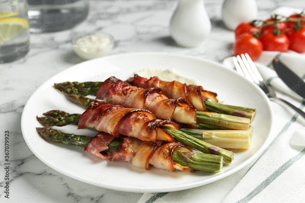 Oven baked asparagus wrapped with bacon on white marble table Oven baked asparagus wrapped with bacon on white marble table